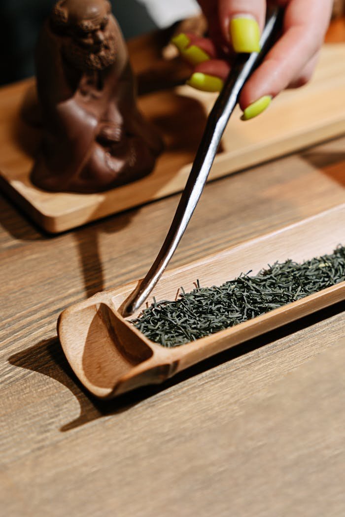 A hand carefully prepares loose leaf tea in an elegant, traditional tea ceremony setting.